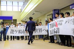 お祝いの横断幕を掲げ、楢崎選手を待つ職員たちとその中を歩く楢崎選手